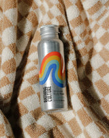 A Mind and Body Wash Travel Size bottle sits on a beige and white checkered towel.