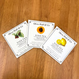 Three Peach Iced Tea - 1 Gallon Envelope packets from Oliver Pluff & Co. sit on a wooden table.