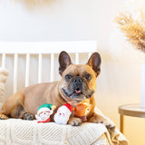 A French Bulldog sits on a blanket with the Never Sleigh Never Dog Toy Set, looking at the camera.