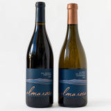 Two bottles from the Alma Rosa Craft Connoisseur Gift Box stand side by side: the left is a 2022 Sta Rita Hills Pinot Noir with a dark blue label, and the right is an El Jabali Chardonnay with a copper-colored cap and matching label style.