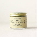 A glass jar with a gold lid labeled “Circular Living Balancing Face Mask” sits on a light surface with a plain background. This mineral-rich mask is ideal for organic skincare and contains Matcha & French Green Clay (Net Wt 1.3 oz).