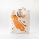 The California Map Tote is a cream recycled canvas bag featuring an orange illustrated map of California with landmarks, a sun, palm tree, and “California” script—great as a unique wedding gift or everyday tote.