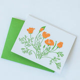 The California Poppy Letterpress Greeting Card Boxed Set features white cards with letterpressed poppy illustrations and green stems, paired with bright green envelopes and set against a light background.