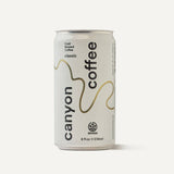 A minimalist white 8 fl oz can of Canyon Cold Brew Coffee with a bronze wavy design.
