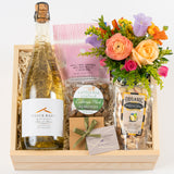 The Cheers Celebration Gift Box includes a bottle of Brick Barn sparkling wine, a bouquet of flowers, apple cider caramels, California Crafted almonds, organic pistachios, chocolates, and more—all beautifully arranged on shredded paper.
