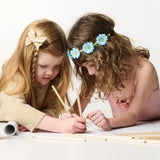 Two young girls draw together with the Colored Pencils - Set of 12, concentrating on their art against a white background.