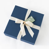 Theopolis Merry Moments Gift Box: a square, navy blue box with a cream satin ribbon and green Yorkville Highlands tag—ideal for gifting Theopolis Vineyards Petite Sirah—shown on a white background.