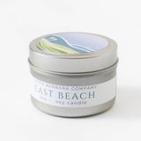 A 3oz silver tin East Beach Travel Candle with a scenic lid illustration, made from soy wax.