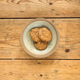 Two Granola Cookies are served in a ceramic bowl on a rustic wooden table.