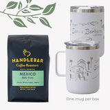 A black bag of Handlebar Coffee Roasters Mexico Bella Vista whole bean coffee and two Santa Barbara, CA illustrated insulated camp mugs are included in the Happy Place Handlebar Coffee Gift Box. Decorative green leaves in top left. Text: One mug per box.