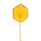 Honeycomb Lollipops are hexagon-shaped amber treats made with organic wildflower honey, featuring a honeycomb pattern on a wooden stick—perfect as sweet tea stirrers.