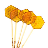 Five hexagonal Honeycomb Lollipops made with organic wildflower honey, each with a honeycomb pattern and "SPARKO" printed on clear sticks—perfect as a sweet treat or tea stirrer.