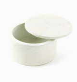 The Natural Soapstone Round Treasure Box is a smooth, white container with subtle gray veining and a matching lid, hand carved by Kenyan artisans and shown partially open.