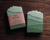 Two green Ojai Trails Ojai Botanika Soap bars, wavy layers; label: 100% vegan white sage soap.