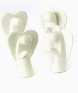 Four Praying Angel Mini Sculptures, handcrafted from white Kisii stone, stand together. Each fair trade figurine features smooth, rounded shapes and large wings, with hands posed differently to suggest unique gestures.