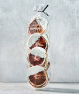 Clear bag of Creme Blood Orange Crisps, half-dipped in white creme chocolate, tied with a black ribbon.