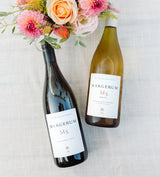 Two wine bottles with 'Margerum' labels - one M5 Red and one M5 White - on a light background with flowers.