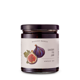 Jar of Savory Fig Jam with caramelized onions, fig image on the label, black lid, shown on a white background.