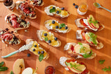 Rustic bread topped with Savory Fig Jam, fruit, cheese, and herbs, beautifully arranged on a wooden board.