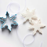 Snowflake Ornament DIY Craft Kit with blue cookie cutter and two white snowflake ornaments on a white background.