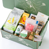 The Sweet & Savory California Care Package is a green gift box packed with Santa Barbara popcorn, pistachios, almonds, gummy bears, a small jar, chocolate, crackers, and a gift card—all beautifully arranged inside.