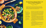 A smoked trout spring salad from Tanya Holland's California Soul, with herbs, peas, nuts, and lemon in a wooden bowl.