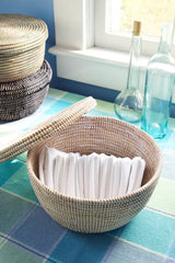 White Lidded Storage Box Basket holds napkins on a plaid tablecloth by glass bottles and a sunny window.