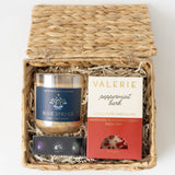 Blue Spruce Holiday Gift Basket with candle, peppermint bark, and a gift box nestled in white shredded paper.