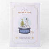 Packaging of Makari & Sons Christmas cookies with a snowman and tree design on a white background.
