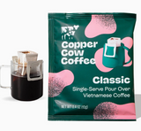 Single-Serve Pour Over Classic Black Coffee packet beside a glass mug of freshly brewed coffee.