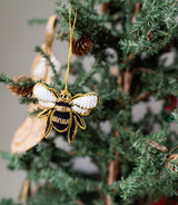 The Embroidered Bee Ornament adds sparkling charm to a green Christmas tree branch.