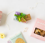 Box of Dark Chocolate Salted Caramel Eggs with green ribbon, cookies, and pink bakery packaging on white background.