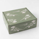 Theopolis Merry Moments Gift Box: green box with white florals and text, closed on a plain background.