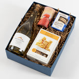 West Coast Treats Box with wine, cheese coins, cookies, jam, and chocolate in a blue crinkle paper-lined box.