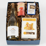 West Coast Treats Box with white wine, cheese coins, alfajores, strawberry candy & festive paper filler.