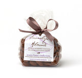 A clear bag of Chocolate Dusted Caramelized Almonds, tied with a brown ribbon, labeled Jessica Foster Confections.