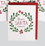 From Santa (Barbara) Christmas Note Cards: Holiday greeting card with a red envelope, featuring a green leaf and berry wreath. "From SANTA Barbara" appears in red and gray lettering; other similar cards are partly visible in the background.