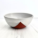 The Handmade Klapp Ceramic Planter, with a matte white glaze and an exposed reddish-brown triangular accent near the base, rests on a white marble surface against a plain white background.