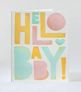 The Hello Baby Letterpress Card features bold yellow, pink, and teal letters spelling HELLO BABY! with a heart for the O on a crisp white background—a cheerful way to welcome a new baby.