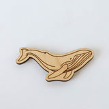 The Humpback Whale Wood Magnet, crafted from sustainably harvested wood with simple laser-engraved details, is shaped like a whale and displayed on a plain white background.
