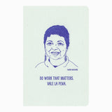 The Inspiring Woman Notebook features a blue line drawing of Gloria Anzaldúa with the quote "Do work that matters. Vale la pena." below her portrait, set against a light background with original illustrations.