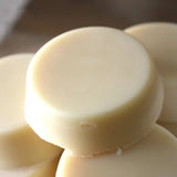 A close-up of several smooth, round Jasmine Mint Organic Lotion Bars stacked together. The glossy, creamy surface highlights the handmade quality of each off-white bar.