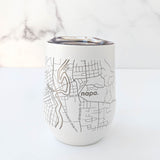 The Map of Napa Insulated Wine Tumbler is a white, insulated drinkware with a stainless steel lid and an engraved gray Napa map design. "napa." appears on the marble-like background.
