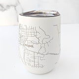 The Map of Napa Insulated Wine Tumbler, made from white stainless steel, features a black line map with labeled streets and the word "Napa," shown on a white surface against a marble background.