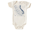 The Organic California Baby Gift Basket includes a cream-colored organic cotton onesie with a blue illustrated map of California, featuring landmarks, animals, and CALIFORNIA text—an ideal unique gift for babies.