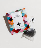 A Petite Coffee and Tea Gift Box sits beside a pyramid-shaped tea bag with a white tag, all displayed on a light background.