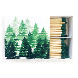 Pine Tree Matches come in a partially open box with green-tipped winter matches and a watercolor pine tree illustration—perfect for lighting holiday candles.