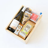 The Stolpman Wine & Snacks Gift Box includes Stolpman Vineyards white wine, gourmet popcorn, organic pistachios, cookies, dried apple slices, crackers, and a small chocolate bar—a refined California artisan gift selection.