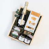 The À Votre Santé Gift Box includes Chandon sparkling wine, Rustic Bakery crackers, California dried apricots, roasted almonds, and two small jars of spreads in a wooden box—an ideal virtual event gift.