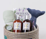 Fair trade woven basket filled with baby bedtime accessories including bath products and a stuffed toy